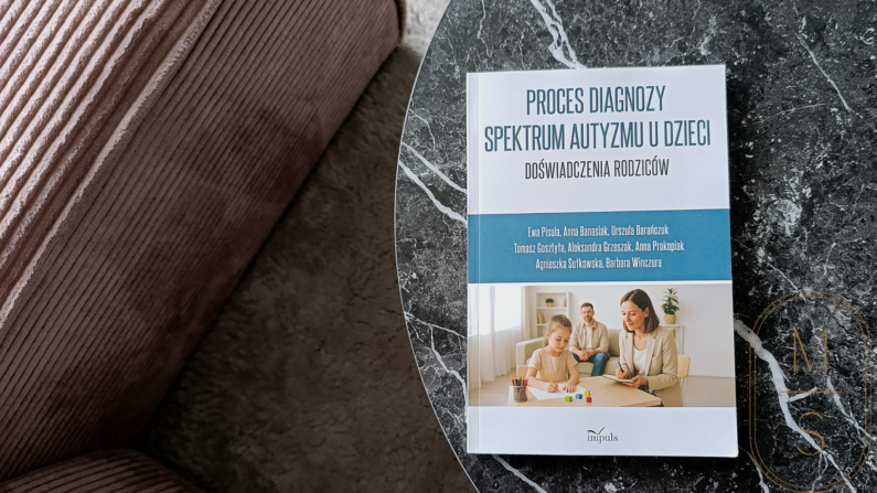 na czarnym marmurowym stoliku leży książka “Proces diagnozy spektrum autyzmu u dzieci. Doświadczenia rodziców”